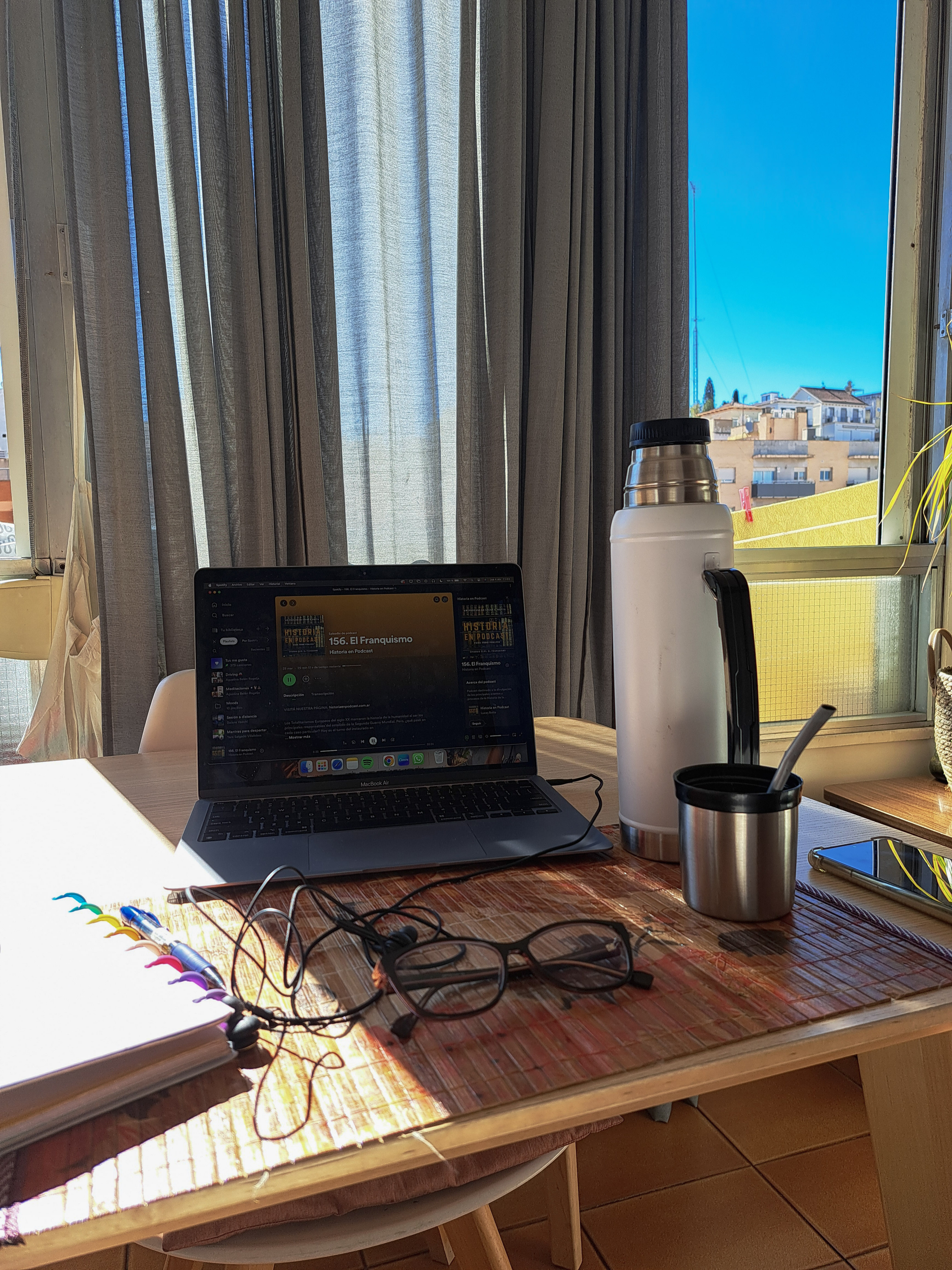 Escritorio con notebook, mate y anteojos junto a la ventana
